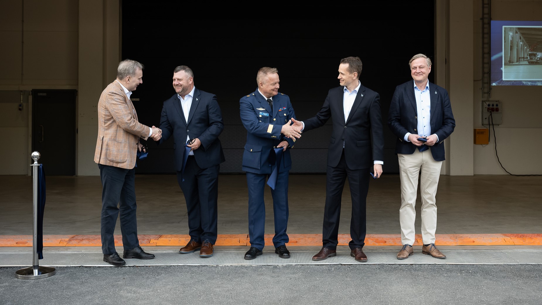 Patrian toimitusjohtaja Esa Rautalinko; Lockheed Martinin Aeronautics Operations -yksikön johtaja Nick Drazic; Insinööriprikaatikenraali, Puolustusvoimien logistiikkalaitoksen apulaisjohtaja Juha-Matti Ylitalo; F-35-hankejohtaja. eversti evp. Henrik Elo, ja Patrian F-35-hankejohtaja ja Executive Vice President, Sales &amp; Marketing Petri Hepola kättelevät avajaisissa.