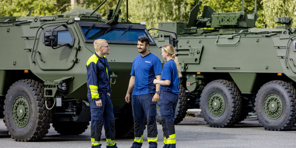 Three Patrians stand next to Patria 6x6 armoured vehicles.