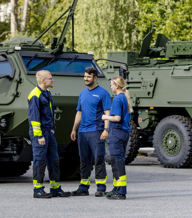 Three Patrians stand next to Patria 6x6 armoured vehicles. 