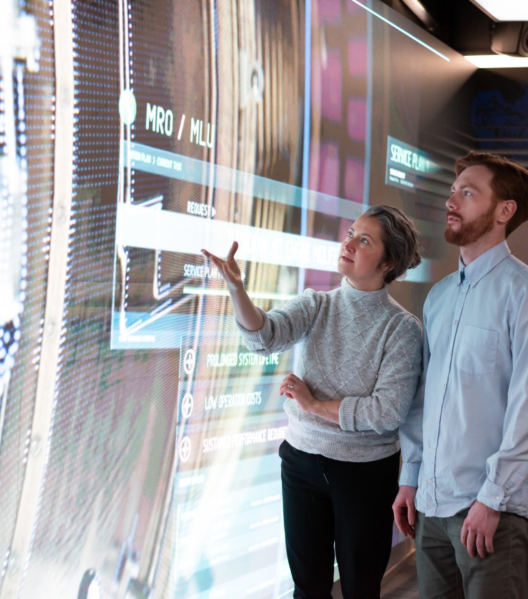 Two people talking while looking at a big screen.