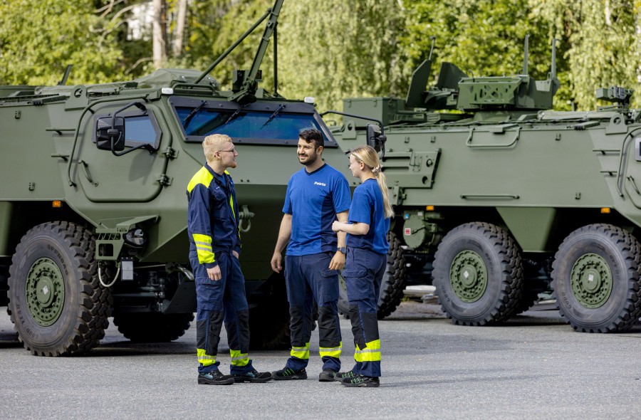 Three Patrians stand next to Patria 6x6 armoured vehicles.