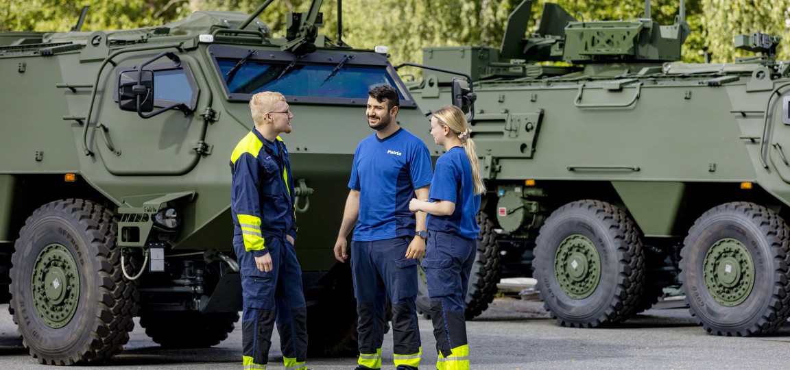 Three Patrians stand next to Patria 6x6 armoured vehicles.