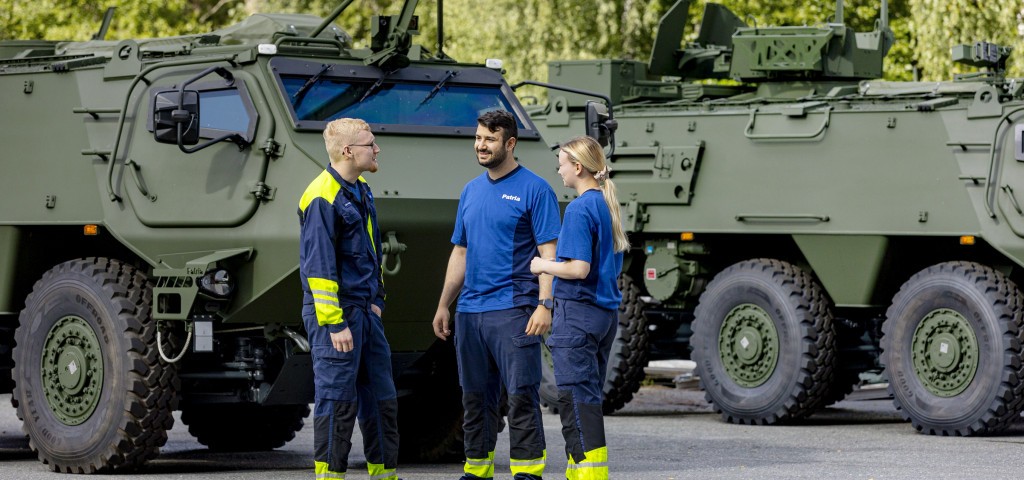 Three Patrians stand next to Patria 6x6 armoured vehicles. 